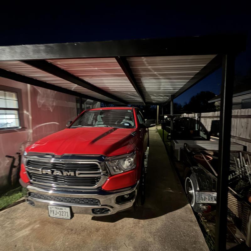 Metal carport installation in residential driveway at night