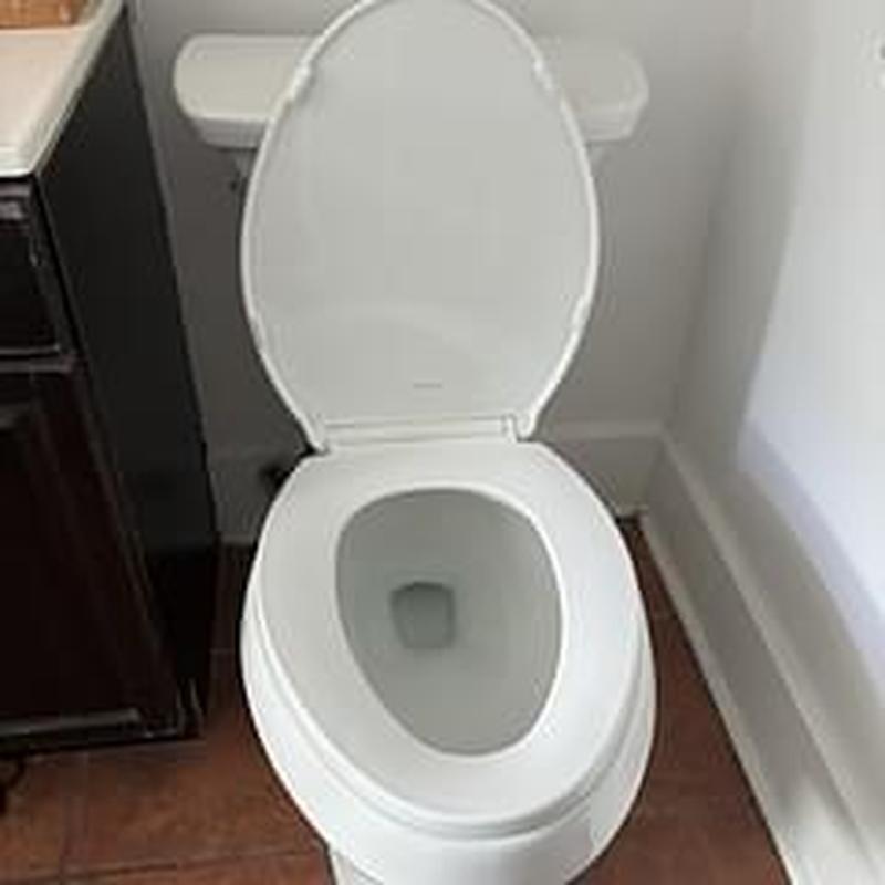 Toilet with raised lid installed in bathroom