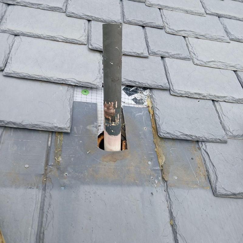 Synthetic roofing tiles around vent pipe on roof
