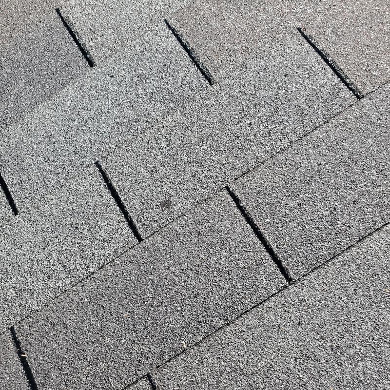 Asphalt shingle roof with wind and hail damage close-up