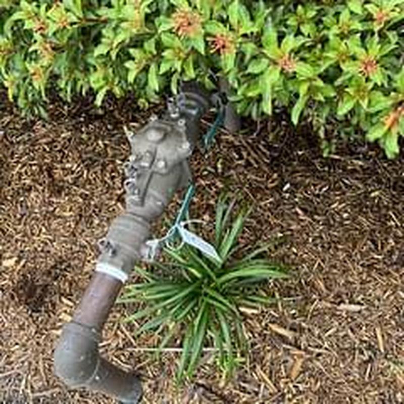 Backflow prevention device with attached pipe outdoors