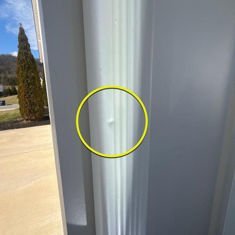 Metal gutter dent damage highlighted by yellow circle