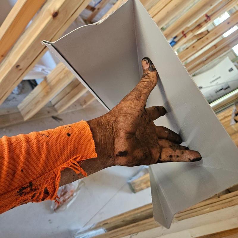 Metal edge flashing held by worker during roof installation