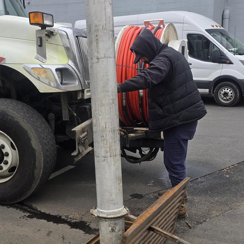 Storm basin Vactor hose setup by technician in parking lot Storm basin Vactor hose setup by technician in parking lot