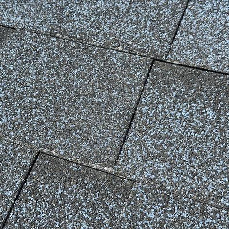 Asphalt roof shingles with visible wear and granule loss