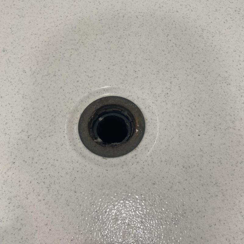 Shower drain opening in white bathtub surface