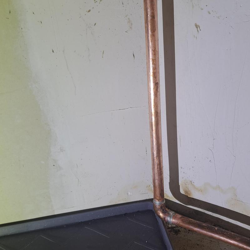 Copper cold water line under kitchen sink near wall corner
