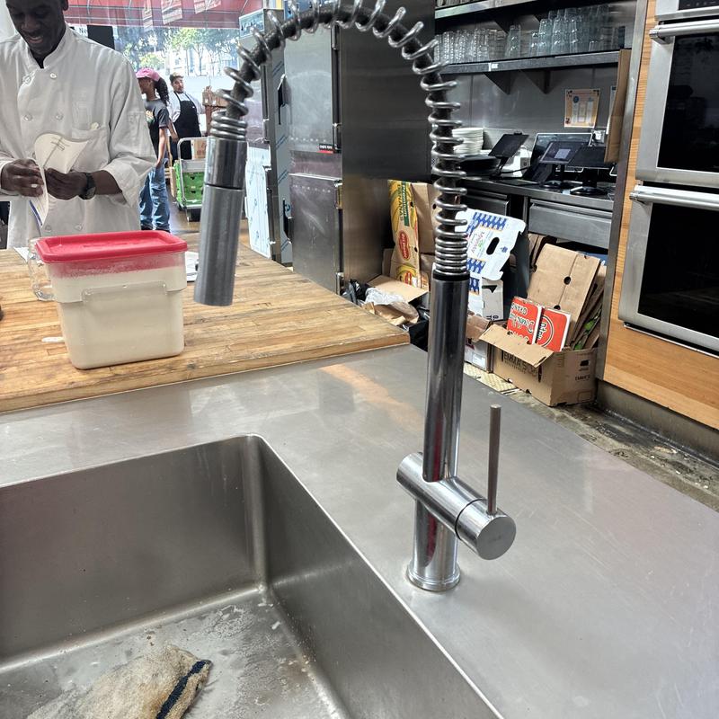 Commercial kitchen pre-rinse faucet installed on stainless sink
