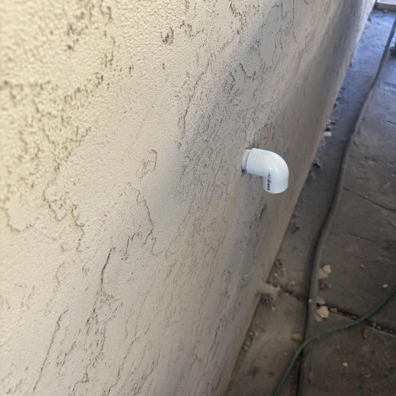 Water heater pan drain pipe elbow exiting stucco wall