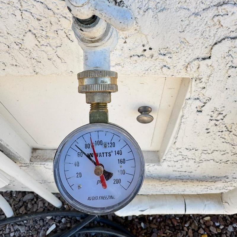 Pressure gauge on irrigation water line near home exterior