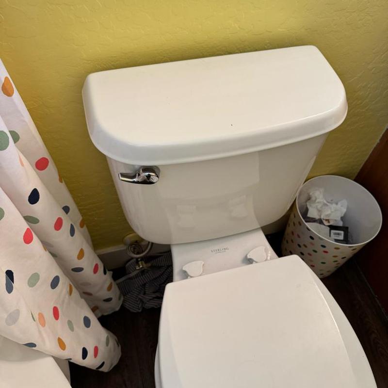 Toilet tank with chrome flush handle in bathroom corner Toilet tank with chrome flush handle in bathroom corner