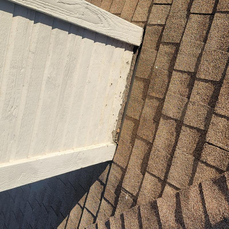 Roof shingles with hail impact damage near siding trim
