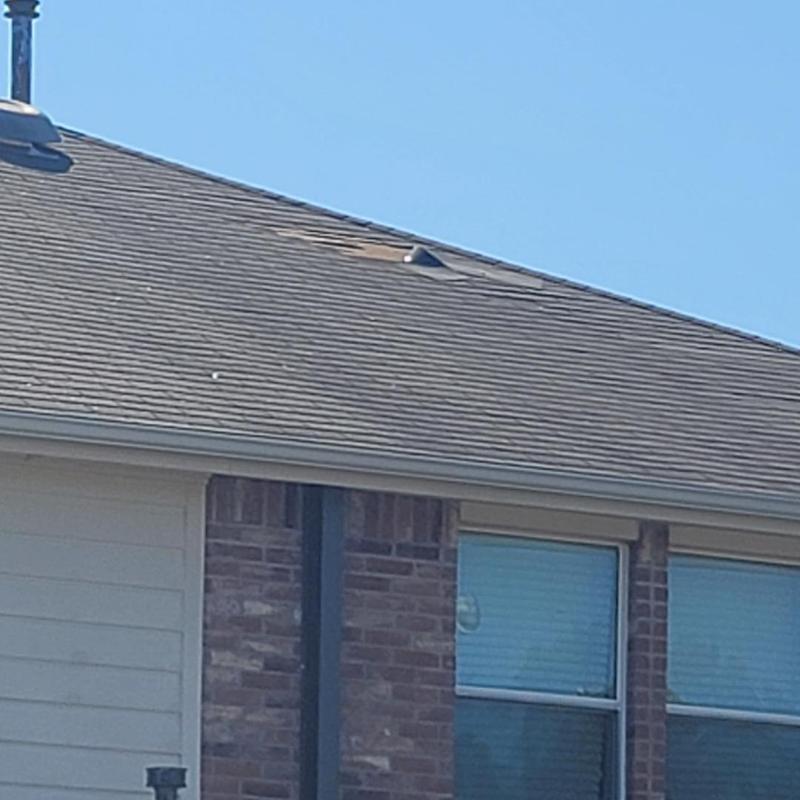 Asphalt shingle roof with hail damage near chimney