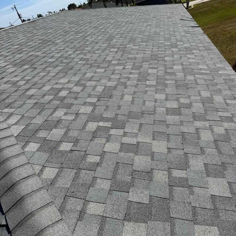 Gray asphalt shingle roof with wear and repairs