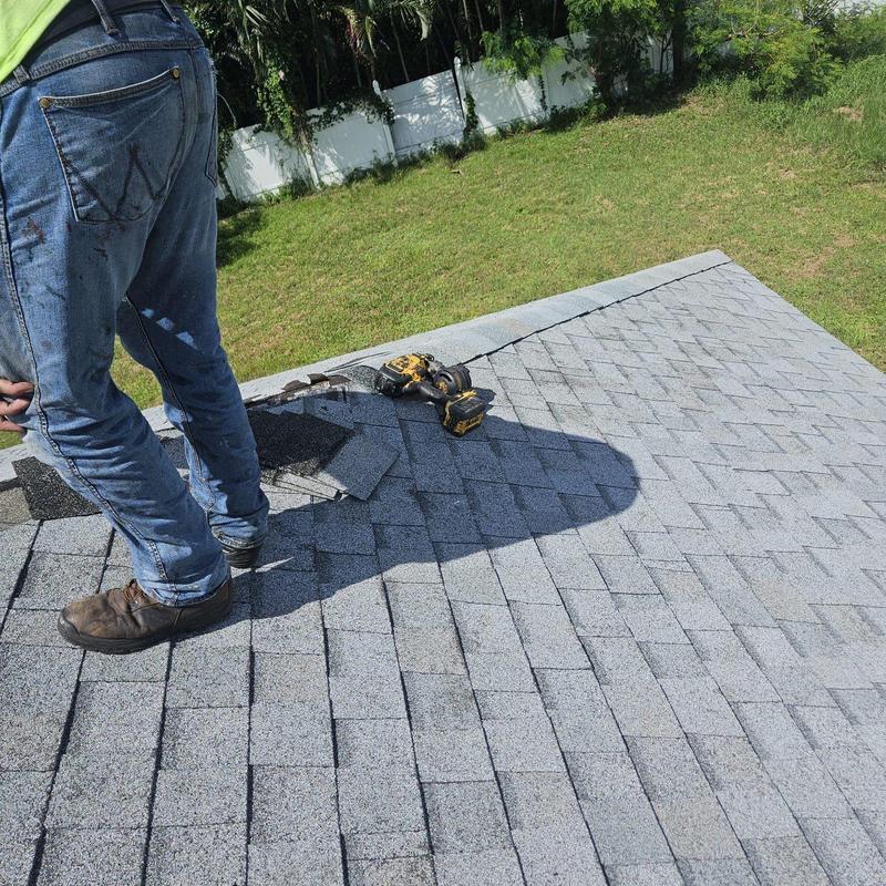 Shingle roof with repair tools and worker on site