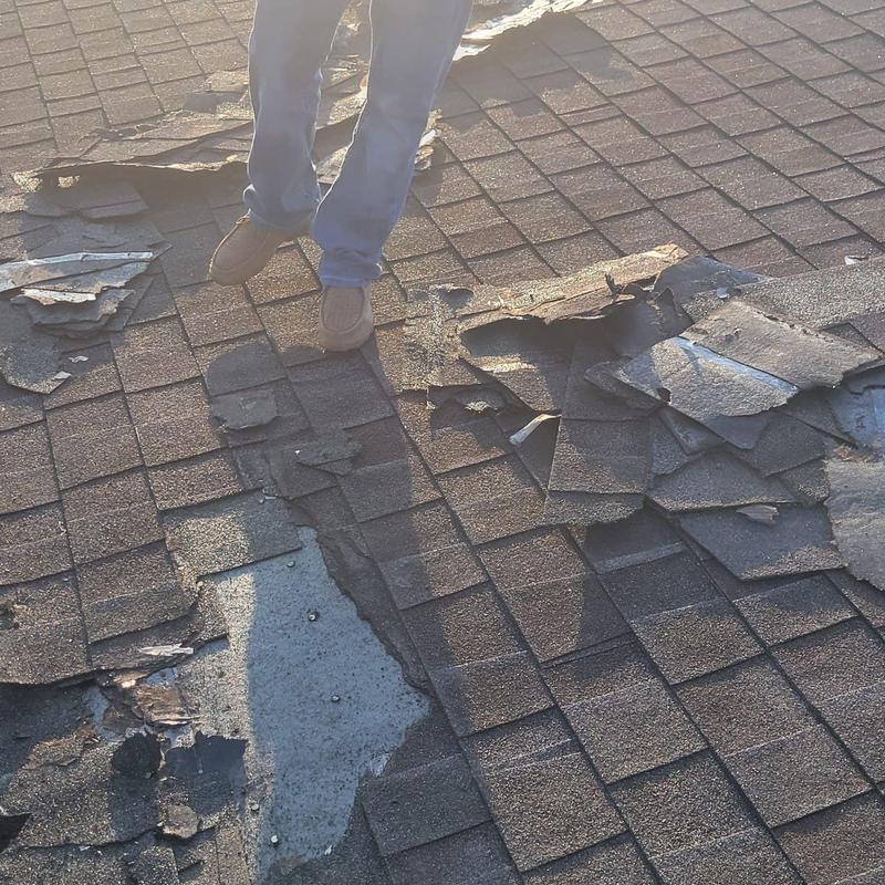 Asphalt shingles with damaged, peeling sections on roof
