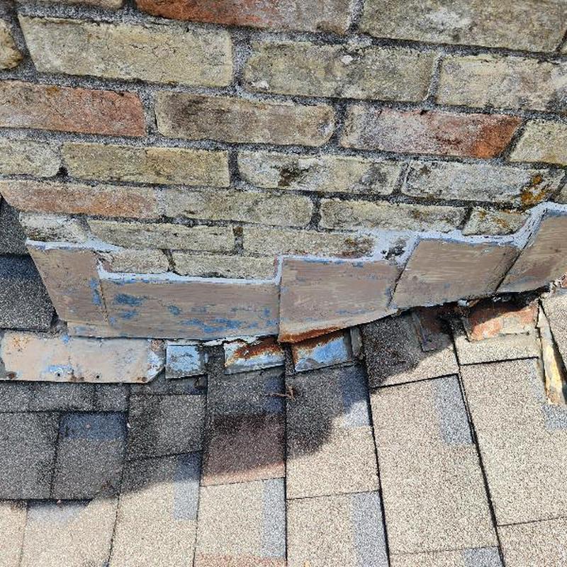 Chimney flashing with worn shingles on roof edge