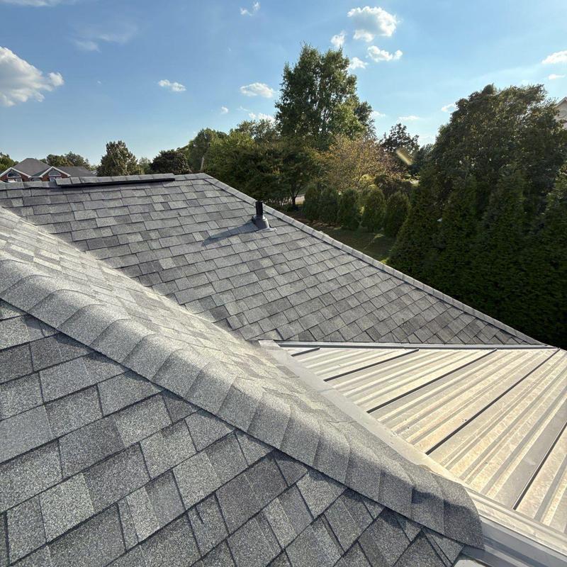 Asphalt shingle roof with ridge cap and metal panel sections