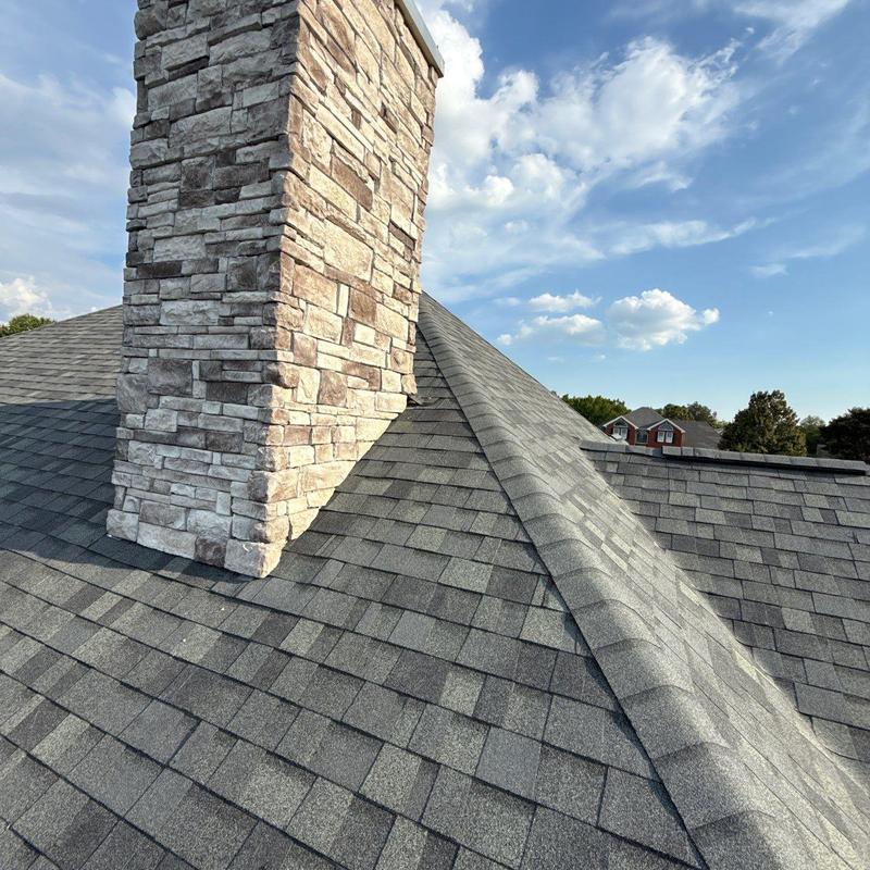 Asphalt shingle roof with stone chimney and ridge detail