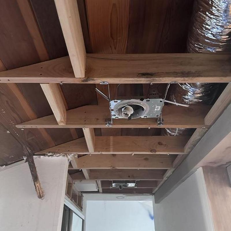 Bathroom exhaust fan housing in exposed ceiling framing