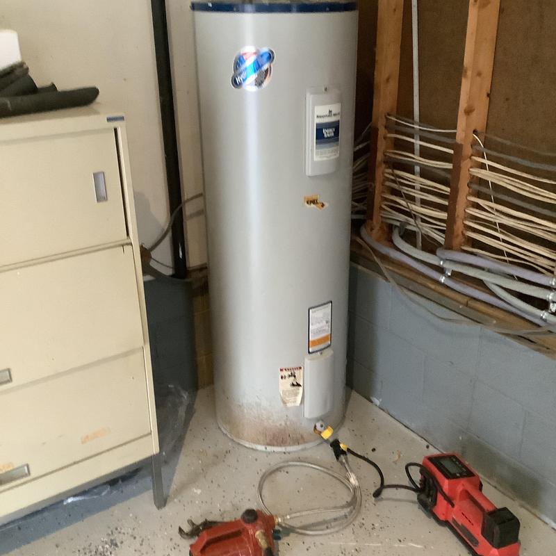 Electric water heater with drain tools in basement