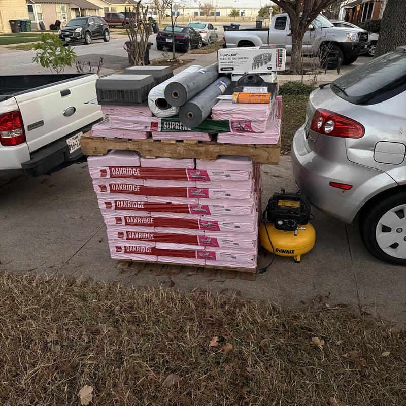 Architectural shingles and roofing supplies stacked outdoors