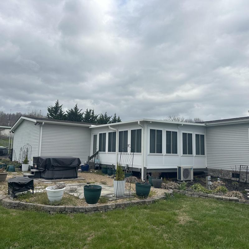 Sunroom exterior with vinyl siding and landscaping