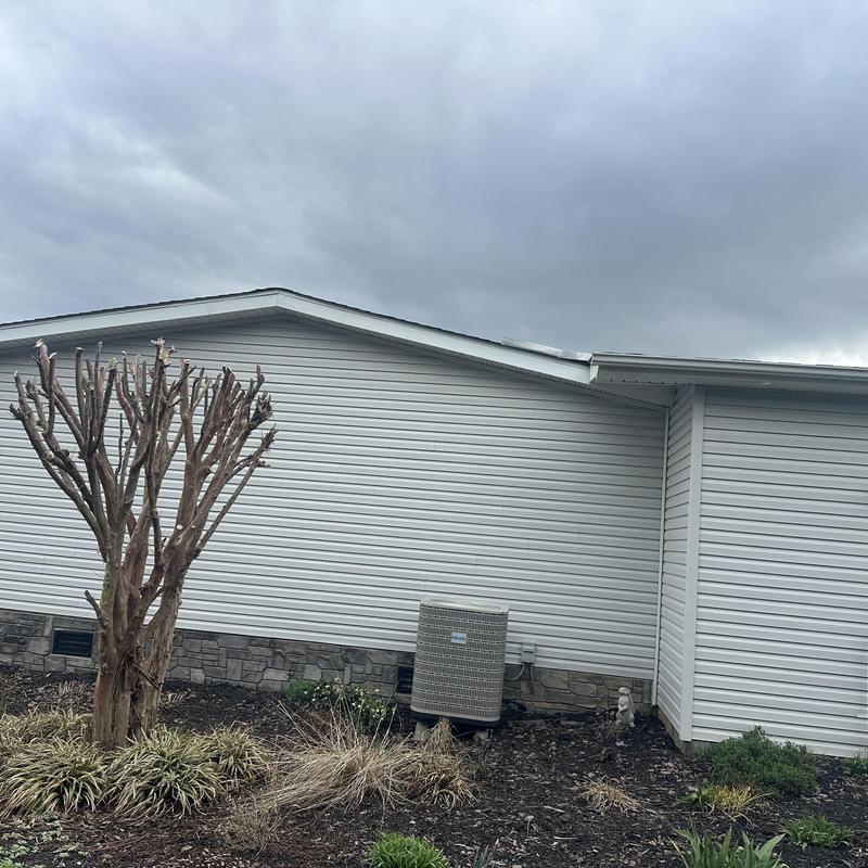 Air conditioner unit outside house with trimmed tree
