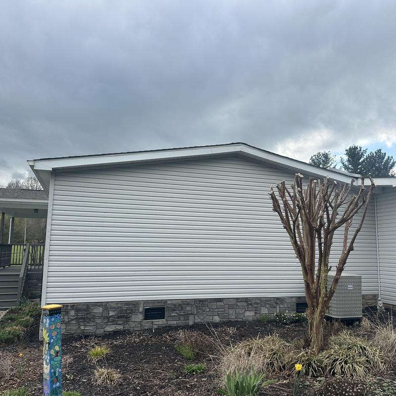 Vinyl siding and stone foundation exterior under cloudy sky