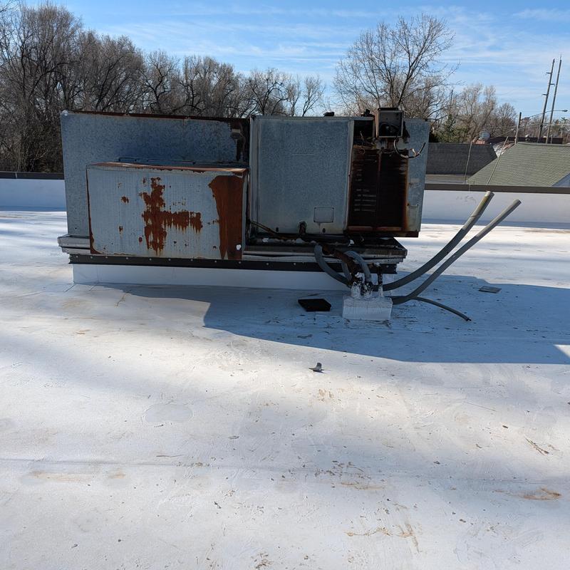Rusted rooftop HVAC unit on white PVC roof