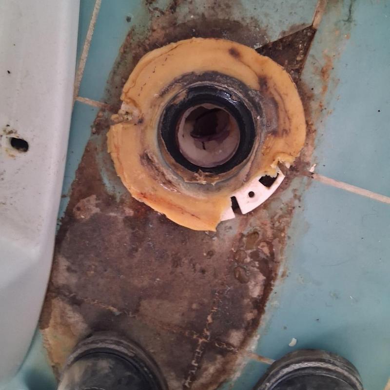 Toilet flange with damaged seal on tiled floor