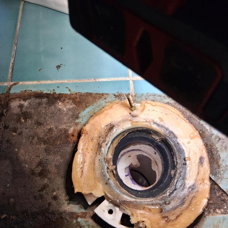 Toilet flange with corroded seal on tiled floor