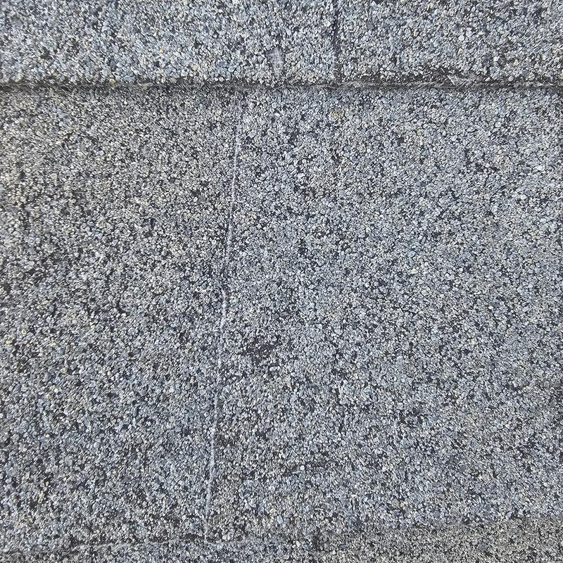 Asphalt shingle roof with hail damage granules close-up