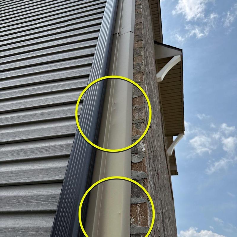 Aluminum downspout with hail impact dents highlighted