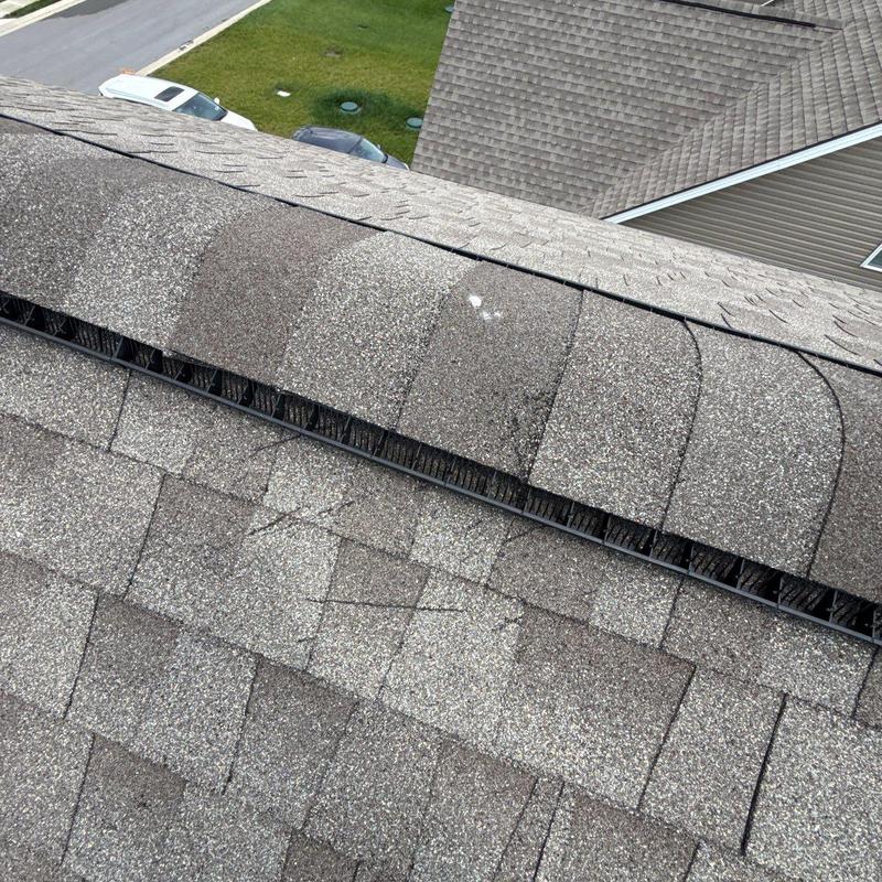 Asphalt shingles with hail impact damage on ridge vent