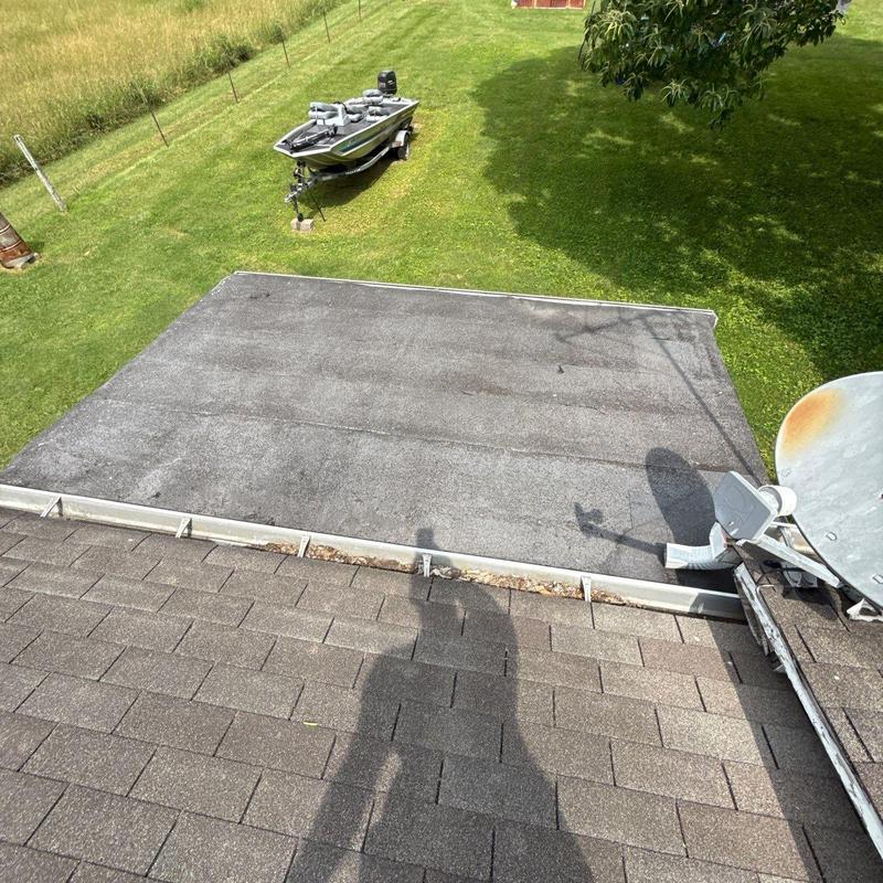 Flat roof with weathered shingles and satellite dish