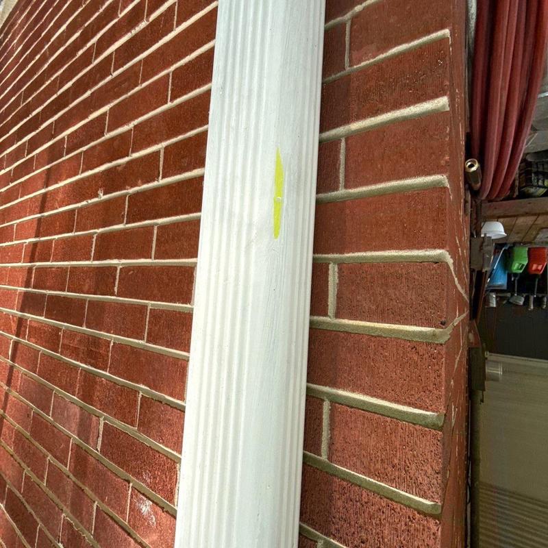 Downspout on brick wall with yellow mark