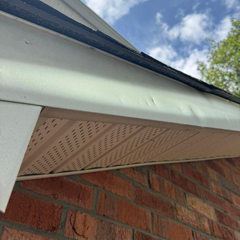 Fascia board dented near roof edge with shingles lifting