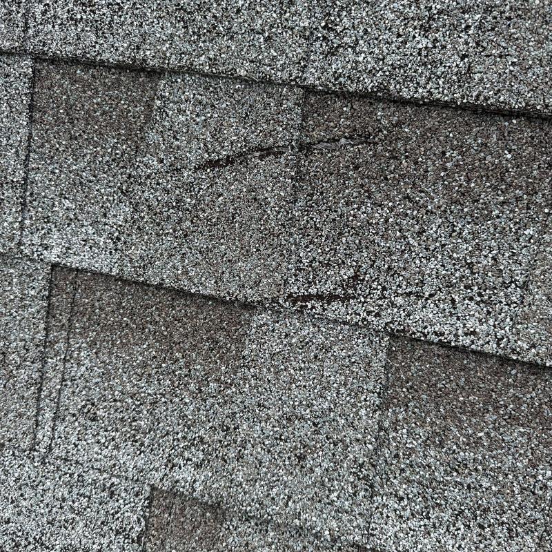 Asphalt shingles showing hail damage and minor wind lifting