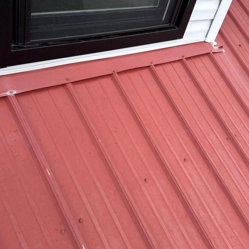 Metal roof panels near door frame with visible hail damage