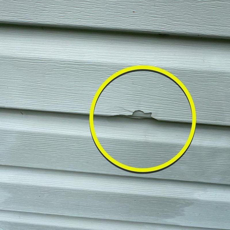 Vinyl siding damage with chipped paint marked in yellow