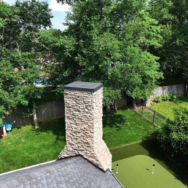 Stone chimney with cap on residential roof