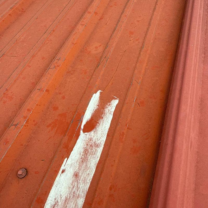 Metal roofing panel with hail damage and paint wear