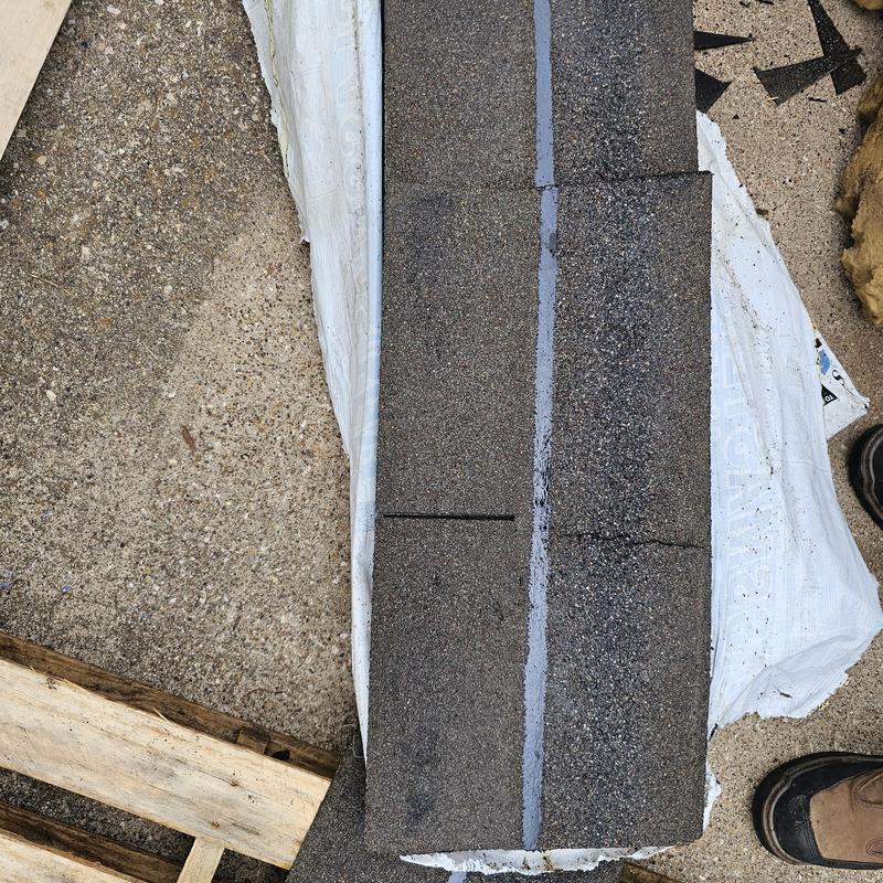 Asphalt roof shingles with hail damage on ground