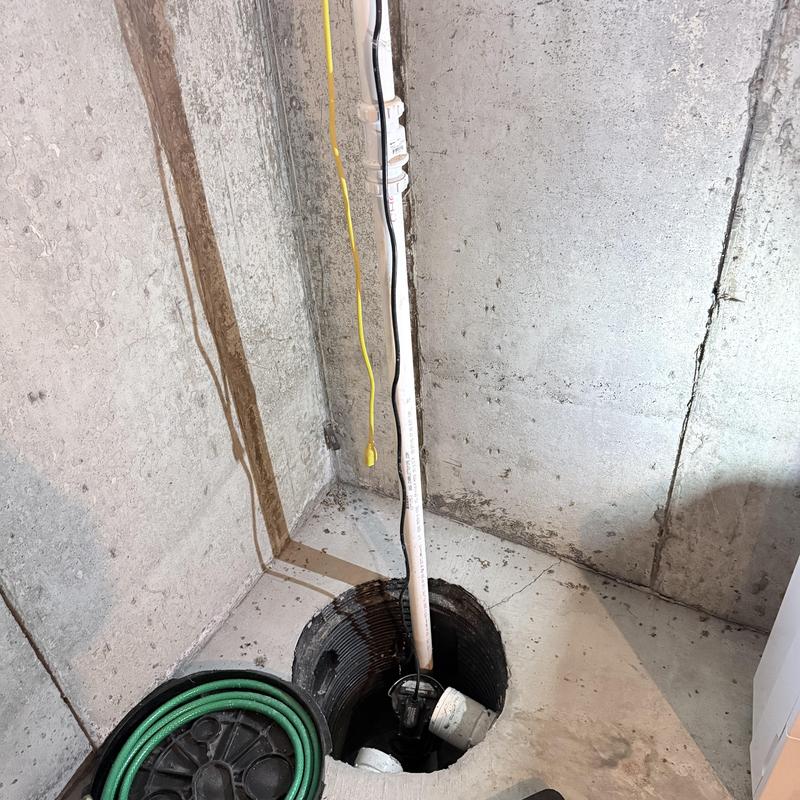 Sump pump installation in basement corner with wiring