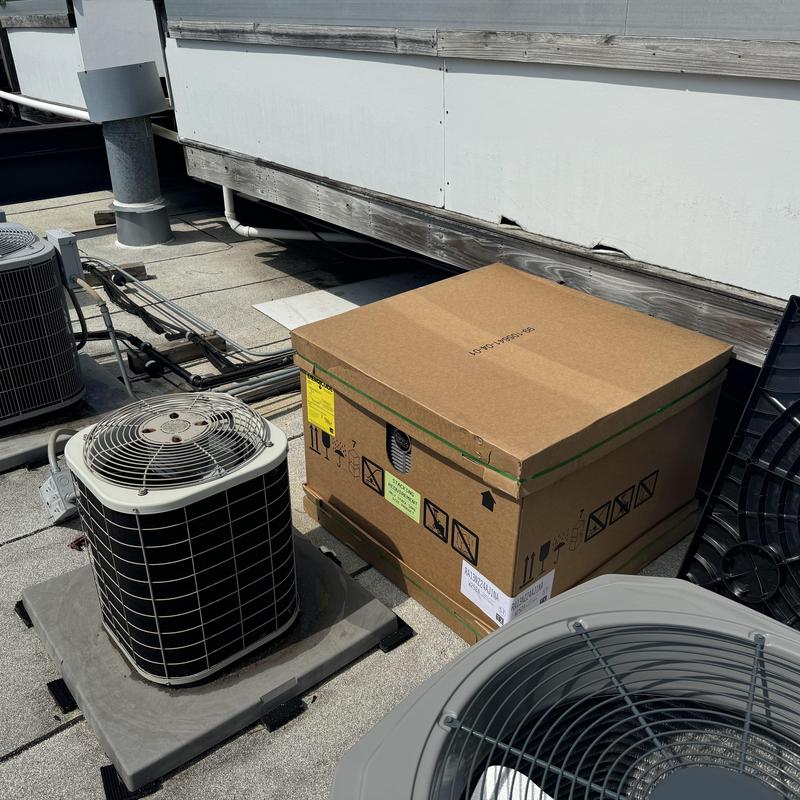 Ruud 14 SEER air conditioner unit on rooftop next to new box