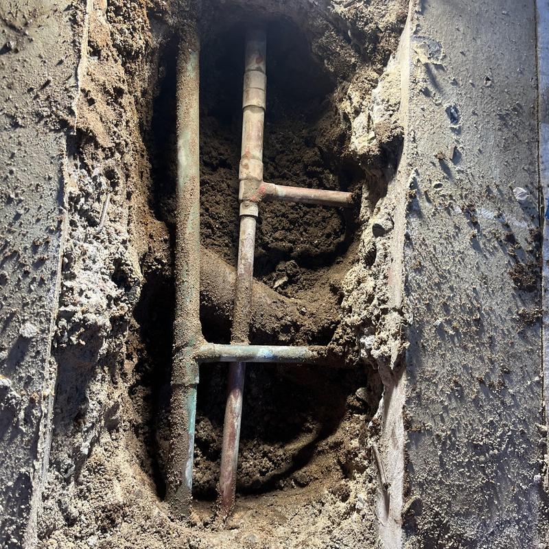 Kitchen hot water pipes exposed in jackhammered slab leak repair