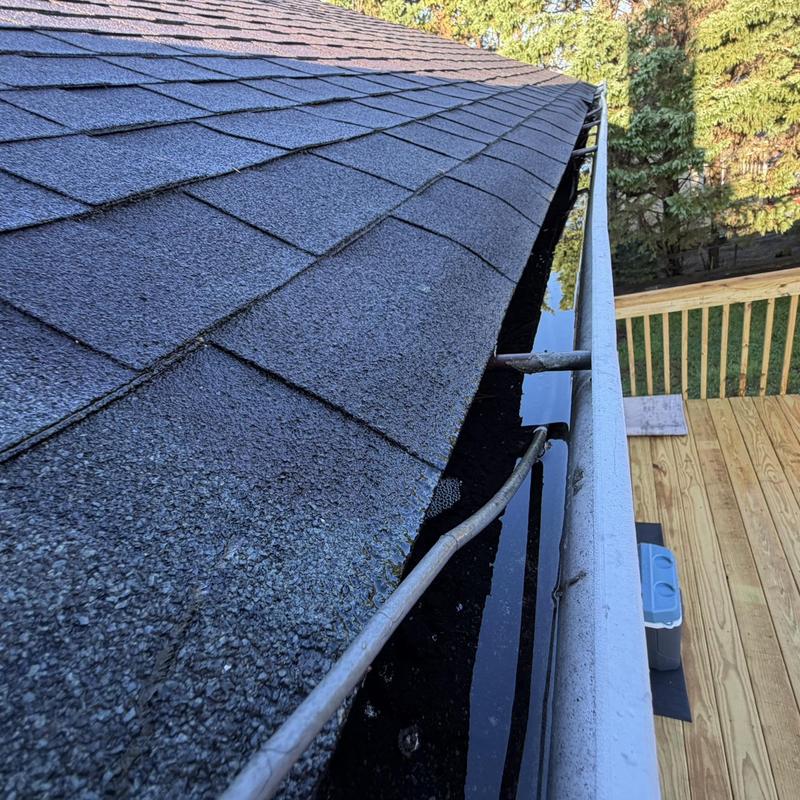 White gutters filled with water near shingled roof edge