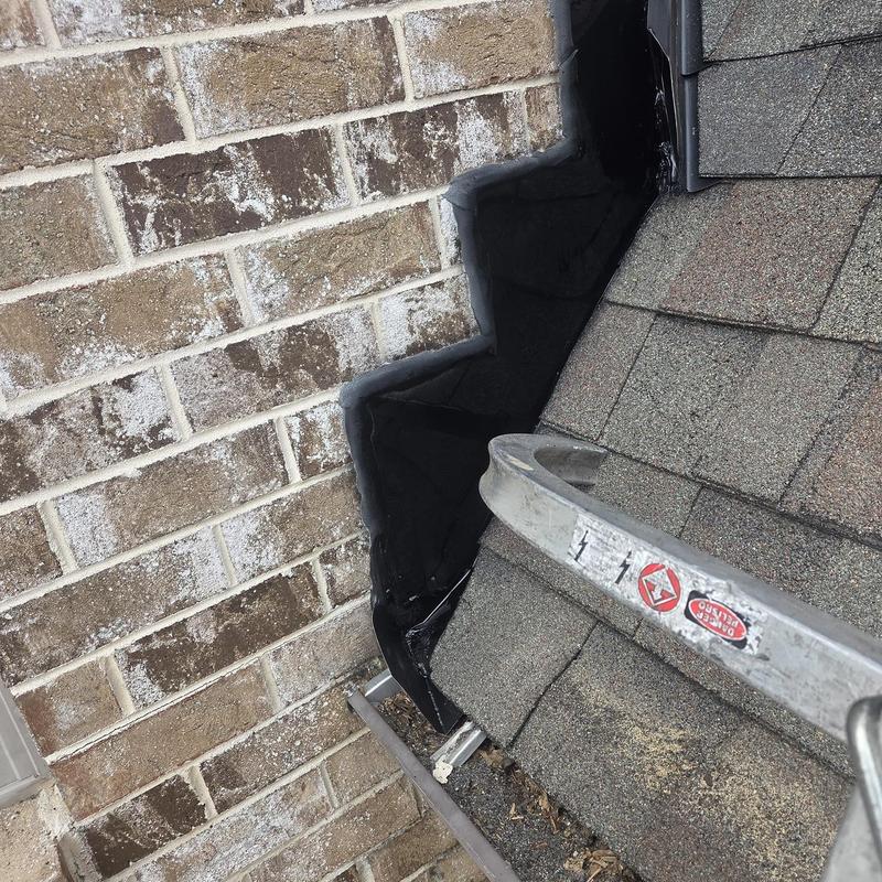 Wall flashing on shingle roof near brick wall