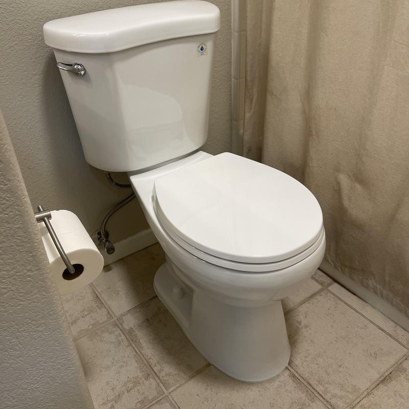 White toilet in upstairs bathroom near shower curtain